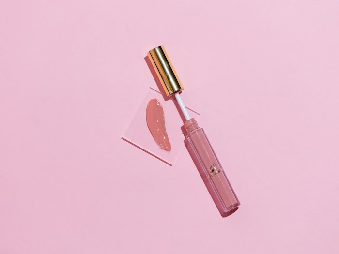 A pink lip gloss on a pink background